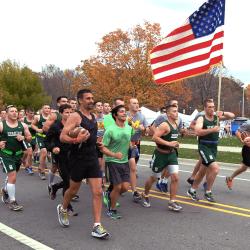 A group of MSU students running together, carrying an American flag