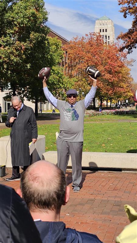 Martino Harmon, VP of Student Affairs at UM holding his arms in the air with both official game balls