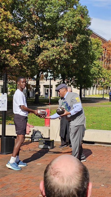 ROTC cadet presenting official game ball to Martino Harmon, VP of Student Affairs at UM