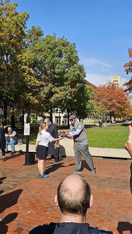 ROTC cadet presenting official game ball to Martino Harmon, VP of Student Affairs at UM