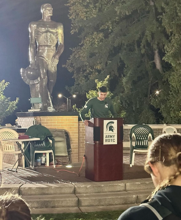 ROTC Cadet speaking at podium in front of Sparty Statue on MSU Campus at Launch Ceremony